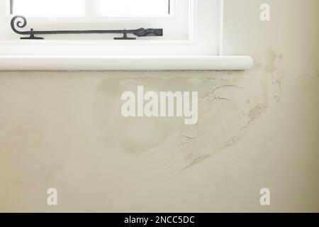 Damp patch under a window of a solid brick wall due to rain penetrating brickwork of old UK house Stock Photo