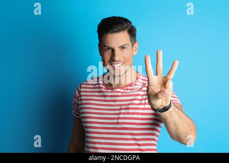 Man showing number three with his hand on light blue background Stock Photo