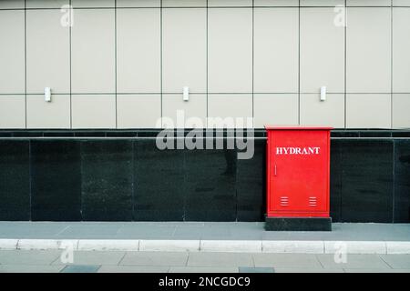 Red fire hose cabinet and extinguisher on the wall in the new building factory with copy space and text Stock Photo