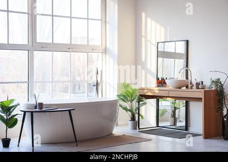 Interior of light bathroom with bathtub, table and mirror Stock Photo