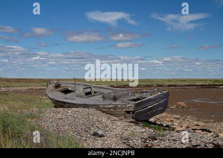 Side view of old wooden boat wrecked and stranded on a rocky shoreline, north of Arviat, Nunavut, Canada Stock Photo