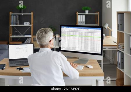 Senior male accountant working in the office and using business spreadsheets on the computer Stock Photo