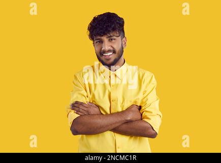 Young ethnic Indian man in stylish shirt smiling broadly posing with arms crossed over chest Stock Photo