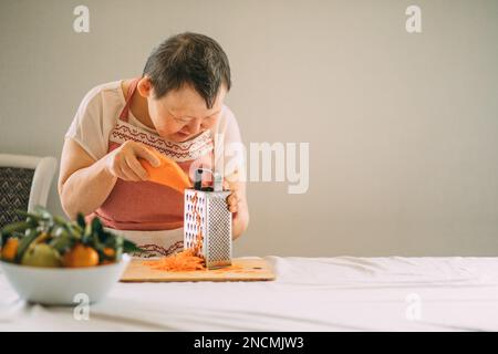 Lifestyle, education. An elderly woman with down syndrome is studying in the kitchen in the classroom Stock Photo