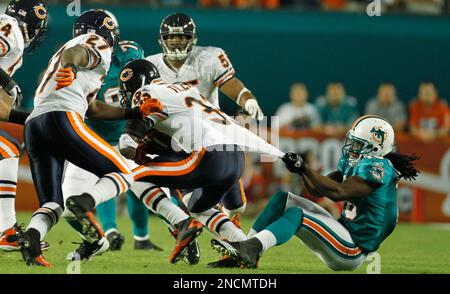 Miami Dolphins' Davone Bess (15) pulls on Chicago Bears' Charles Tillman (33)  jersey after Tillman intercepted a pass as Olin Kreutz (57) applies  pressure during a NFL football game in Miami, Thursday