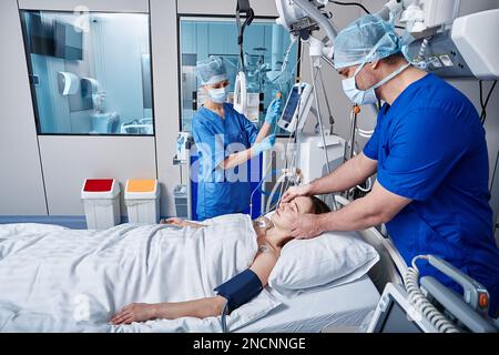 Intensive care patient. Nurses attending to female patient in intensive care unit of hospital Stock Photo