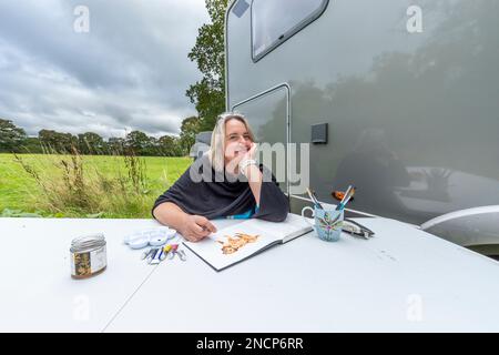 Renowned commercial artist Jo Scott abandons her studio to improve work life balance. Working anywhere in her state of the art, connected motorhome Stock Photo