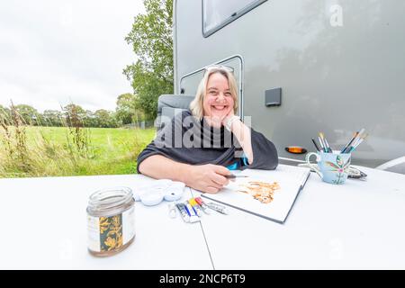 Renowned commercial artist Jo Scott abandons her studio to improve work life balance. Working anywhere in her state of the art, connected motorhome Stock Photo