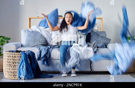 Laundry, frustrated and upset woman in the living room throwing the clothes with anger at her home. Crazy, busy and angry female maid, housewife or Stock Photo