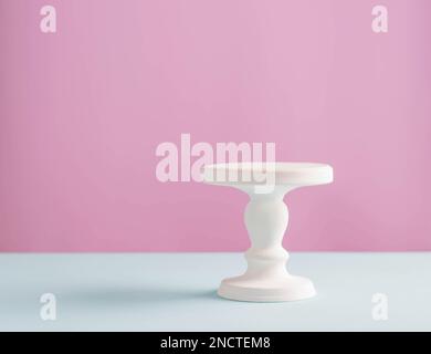 Empty white stand for a birthday cake on a pink plain background Stock Photo