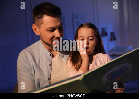 Father reading bedtime story to his daughter at home Stock Photo