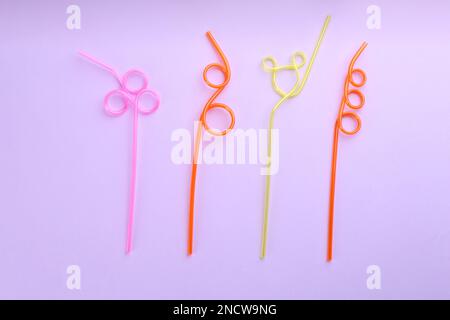 Colorful plastic drinking straws on violet background, flat lay Stock Photo