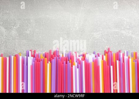 Colorful plastic drinking straws on grey stone table, flat lay. Space for text Stock Photo