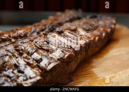Tasty grilled pork ribs on wooden board, closeup Stock Photo