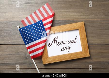 Frame with phrase Memorial Day and American flag on wooden table, flat lay Stock Photo