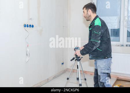 Man makes repairs in new apartment. Builder levels walls using laser level. High quality photo Stock Photo