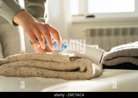 Close-up of a woman using an adhesive roller to remove lint and fluff from a jumper Stock Photo