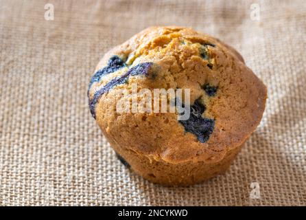 Blueberry muffin on hessian texture close up with copy space - selective focus Stock Photo