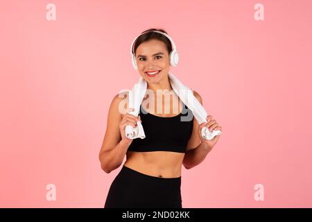 Sporty Young Woman Wearing Headphones Posing With Towel Around Neck After Training Stock Photo