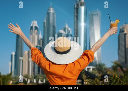 UAE vacations. woman standing with hands raised against Dubai city skyscrapers Stock Photo