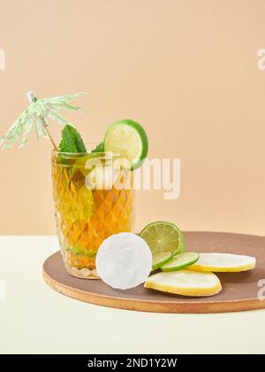 Glass of delicious nonalcoholic cocktail with lime and lemon slices decorated by mint leaves on wooden board Stock Photo