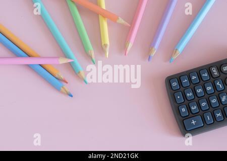 Pastel colored pencils with a calculator, top view on pink background, back to school concept Stock Photo