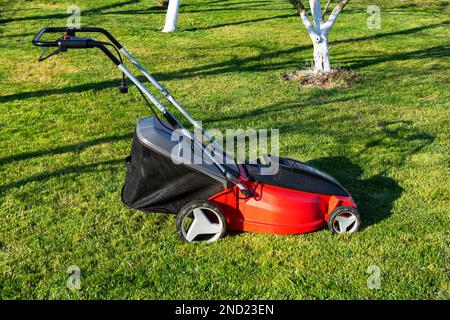 Electric Lawn mower on a green meadow. Garden equipment. Stock Photo