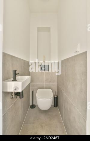 Interior design of washroom with tiled big square beige walls wall mounted toilet and small ceramic sink Stock Photo