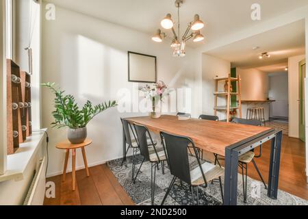 Interior design of light dining room with wooden table and chairs on carpet plants empty frames and white walls Stock Photo