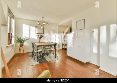 Interior design of light dining room with wooden table and chairs on carpet plants empty frames and white walls Stock Photo