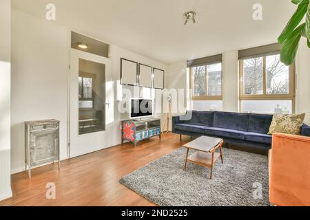 Interior design of spacious light lounge with blue couch cushion coffee table gray shaggy carpet TV on cabinet empty frames wooden laminate and window Stock Photo