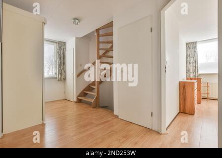 Corridor with wooden stairs and parquet floor against white walls and opened door leading to bedroom in modern apartment Stock Photo