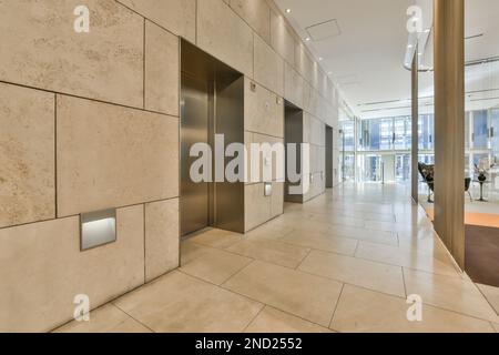 Interior of modern spacious hall with tiled walls and floor against elevator in contemporary hotel building Stock Photo