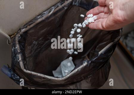 Throwing pills into the garbage - illegal disposal Stock Photo