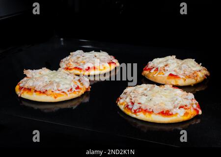 Four baked homemade mini pizzas in electric oven at home Stock Photo