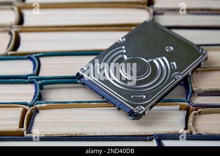 Computer hard drive on the background of a stack of old paper books Stock Photo