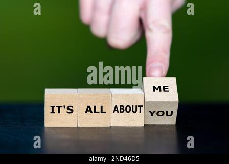 Hand turns dice and changes the expression 'it's all about you' to 'it's all about me'. Stock Photo