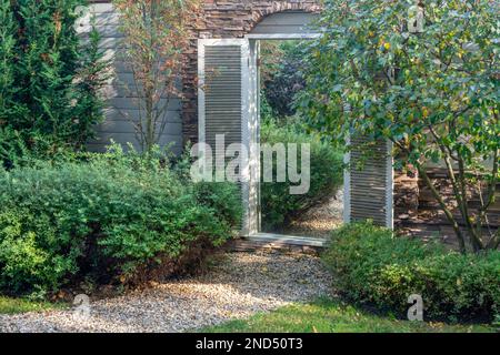 element of landscape design - mirror in the wall od garden - creating the illusion of transition into another space don't existing.  Garden near dacha Stock Photo