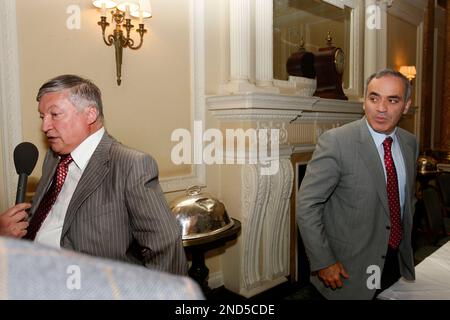 Former World Chess Champion, Garry Kasparov, right, talks to the media as  FIDE presidential candidate and former World Chess Champion, Anatoly Karpov,  left, and President of English Chess Federation, CJ de Mooi listen on  during their World Chess