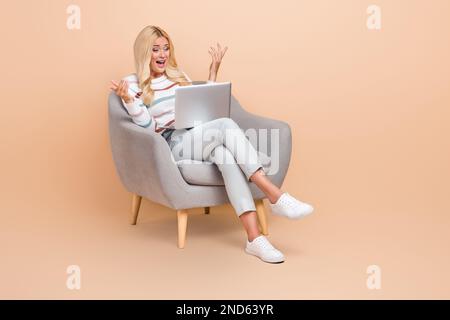 Full body size photo of young surprised woman palms no idea hold laptop video call confused hard work problems isolated on beige color background Stock Photo