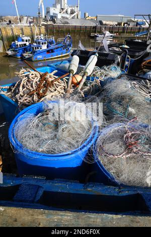 Whitstable, Kent, England, UK. Fishing nets, rope and anchors in baskets on the harbour wall Stock Photo