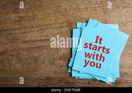 Roles and responsibilities concept. Blue paper cards with phrase It stars with you and space for text on wooden table, top view Stock Photo