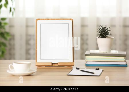 Modern tablet, cup of coffee and stationery on wooden table indoors. Space for design Stock Photo