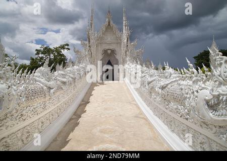 Bridge of the Cycle of Rebirth and the Ubosot of Wat Rong Khun, Chiang Rai, Thailand. Stock Photo