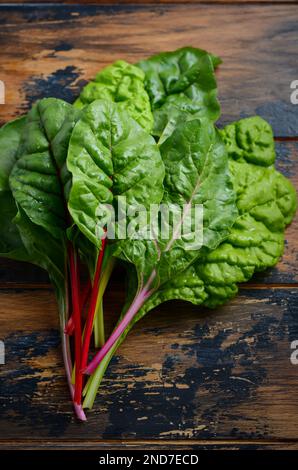 Fresh colorful chard leaves on old rustic wooden background. Stock Photo