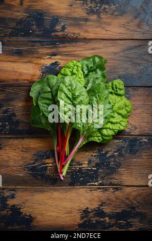 Fresh colorful chard leaves on old rustic wooden background. Stock Photo