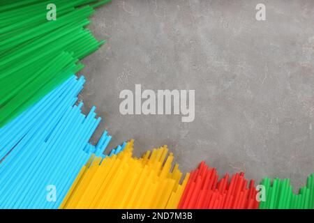 Colorful plastic drinking straws on grey stone table, flat lay. Space for text Stock Photo
