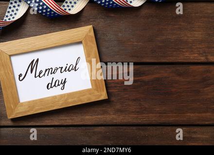 Frame with phrase Memorial Day and ribbon on wooden table, flat lay. Space for text Stock Photo