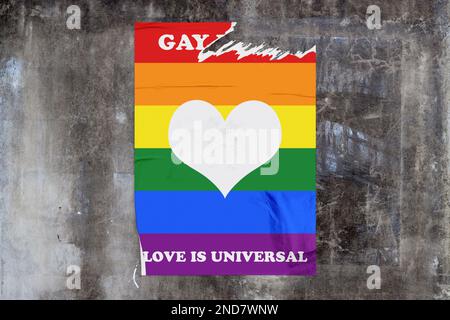 Full-frame weathered concrete wall with a torn rainbow poster in the middle depicting a heart sign with the message "Gay pride - Love is universal" wr Stock Photo