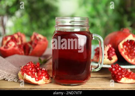 Pomegranate juice in mason jar and fresh fruits on wooden table outdoors Stock Photo